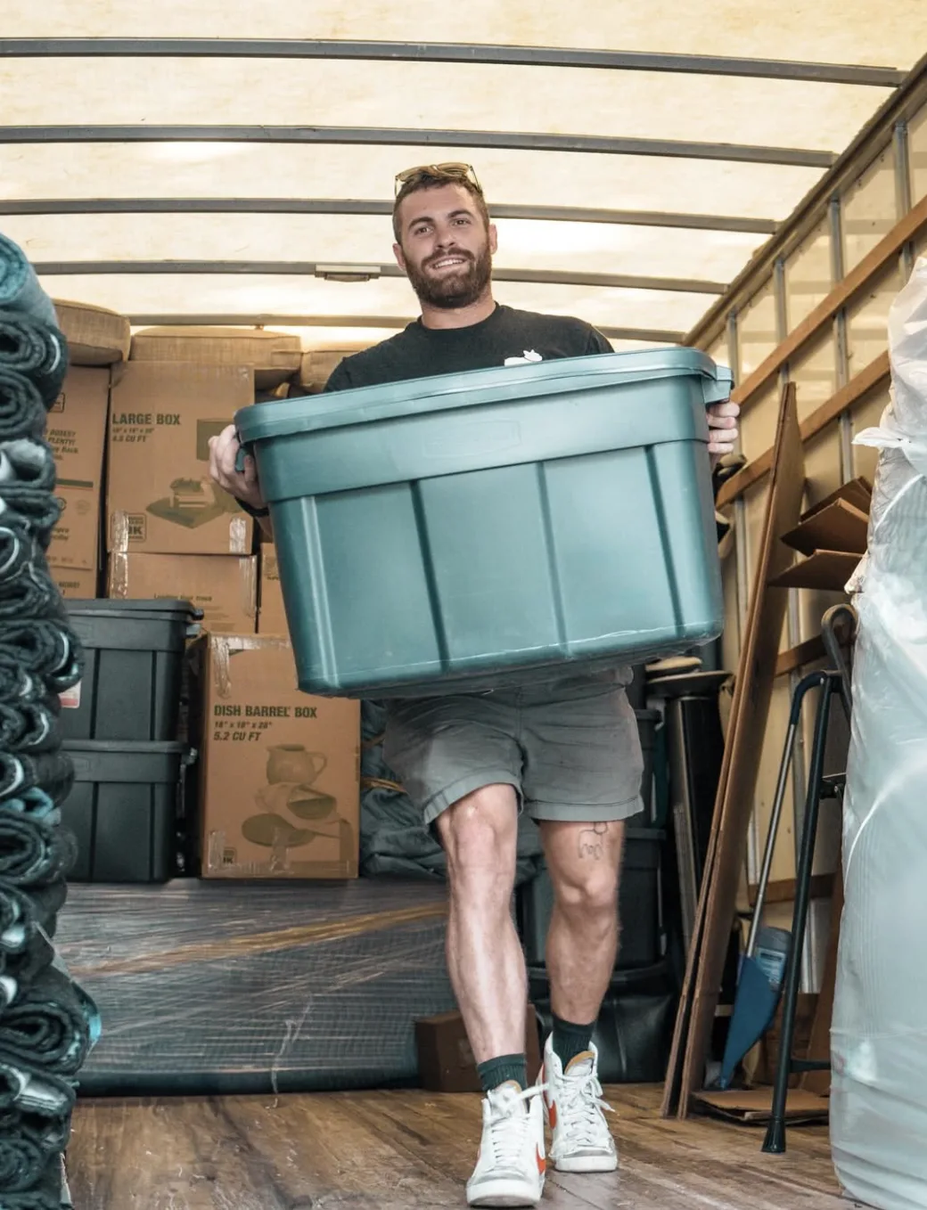 Mover carrying a plastic bin inside a moving truck