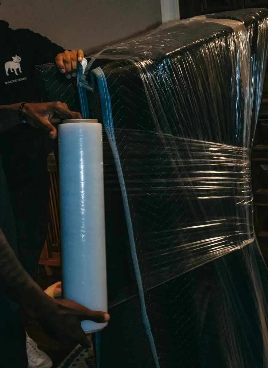 Mover wrapping furniture with stretch wrap before moving it